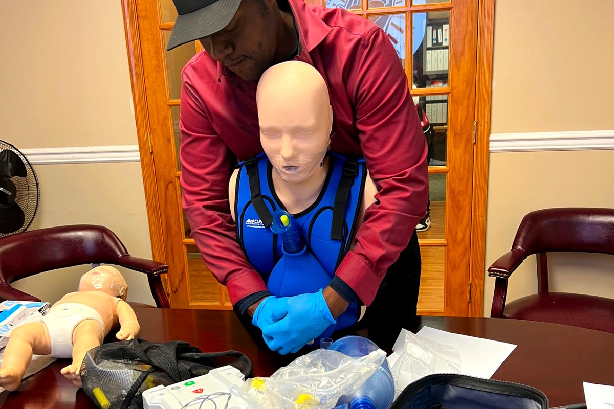 Learner practicing abdominal thrusts on a choking response training vest and manikin