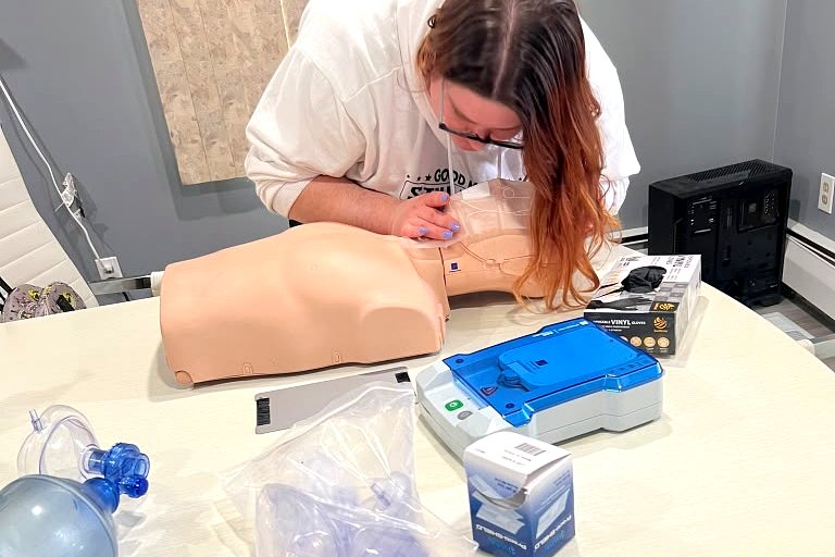 Student checking breathing on an adult manikin during a skills check session